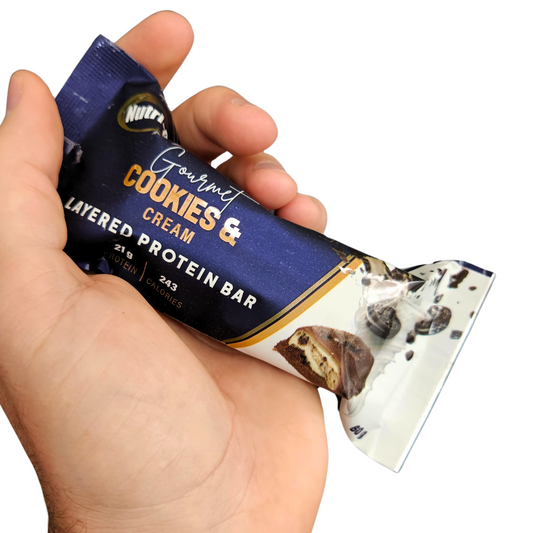 cookies & cream layered protein bar in hand